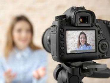 DSLR camera focusing on smiling woman who is blurred in the background