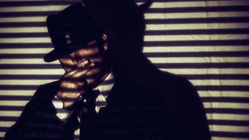 Man smoking behind shadows of blinds