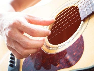 Man plucking strings on acoustic guitar