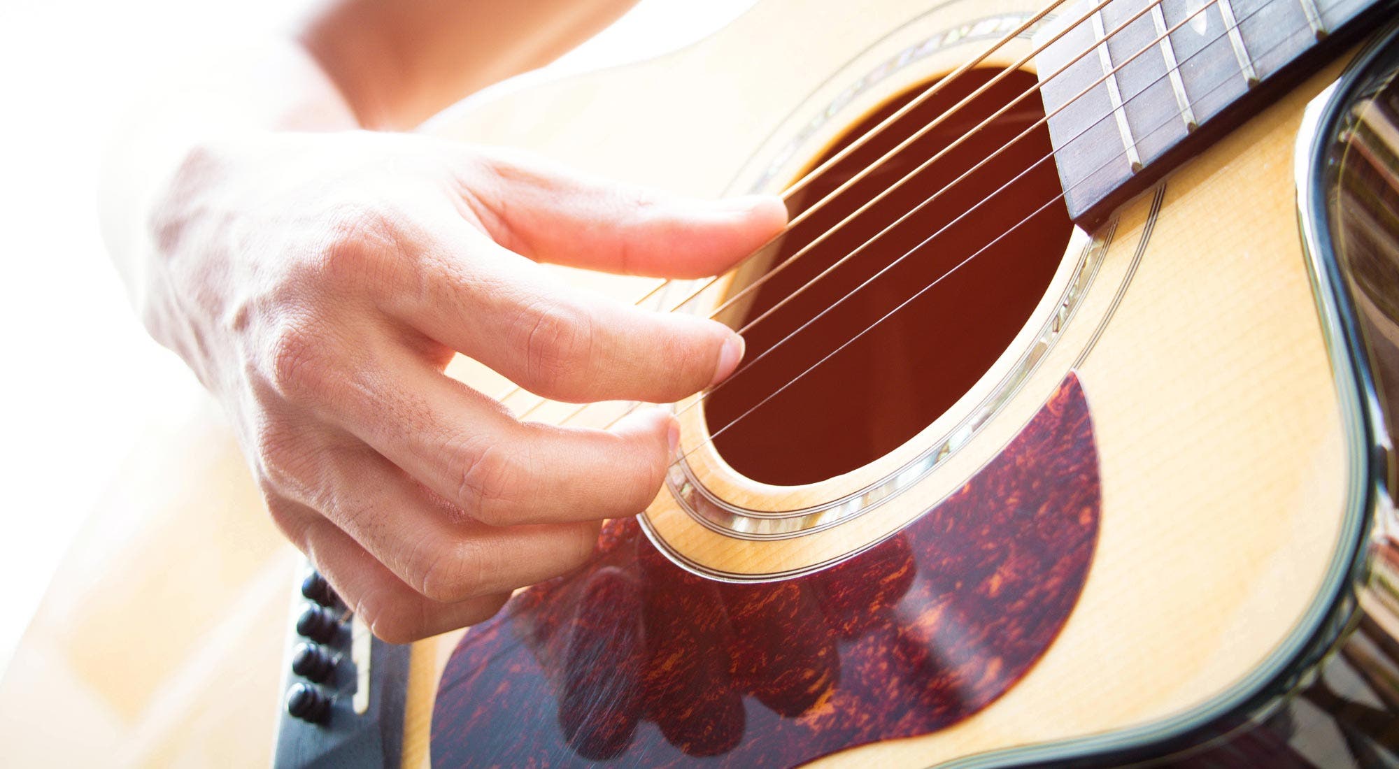 Man plucking strings on acoustic guitar