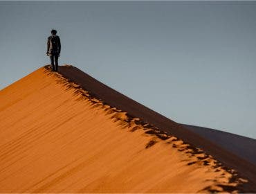 landscape photographer walking on sand dune
