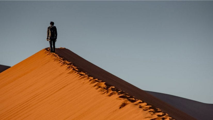 landscape photographer walking on sand dune
