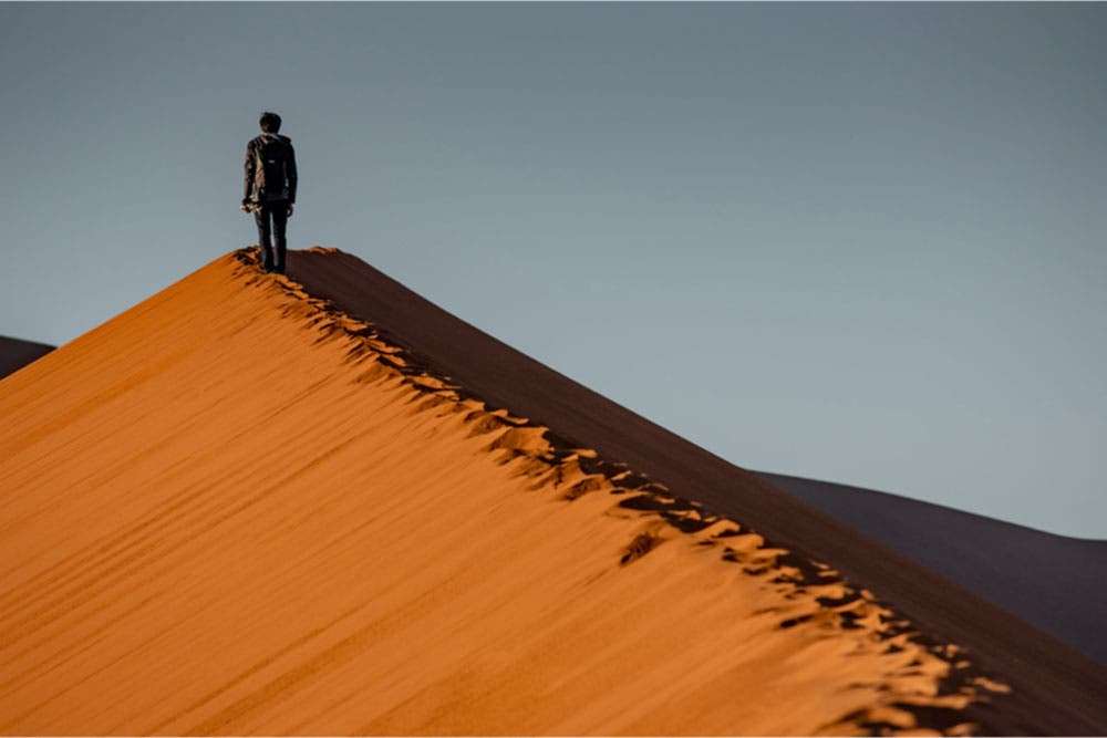 landscape photographer walking on sand dune