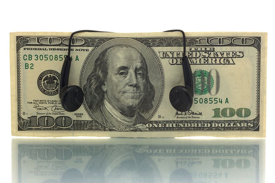 concept shot with a hundred dollar bill and a pair of black earphones