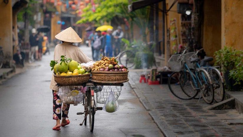 Woman walking in Hoi An with fruits