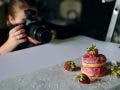 food photographer photographing pink donuts on table with professional camera