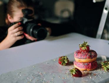 food photographer photographing pink donuts on table with professional camera