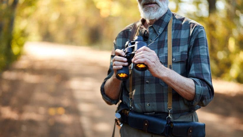 best binoculars for birding, man birdwatching with binoculars in nature forest