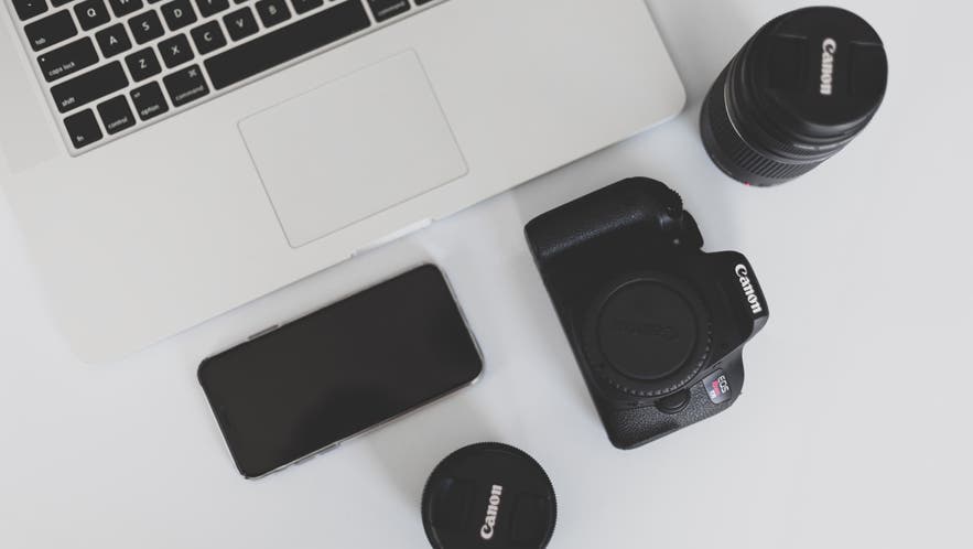 macbook laptop and canon camera and lenses on desk branding tips for creative businesses