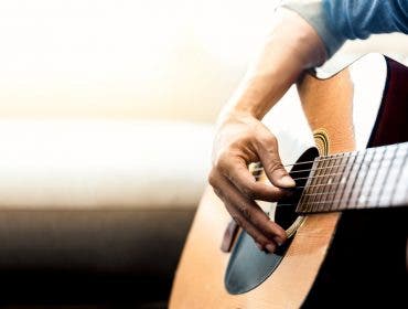 man playing acoustic guitar strings