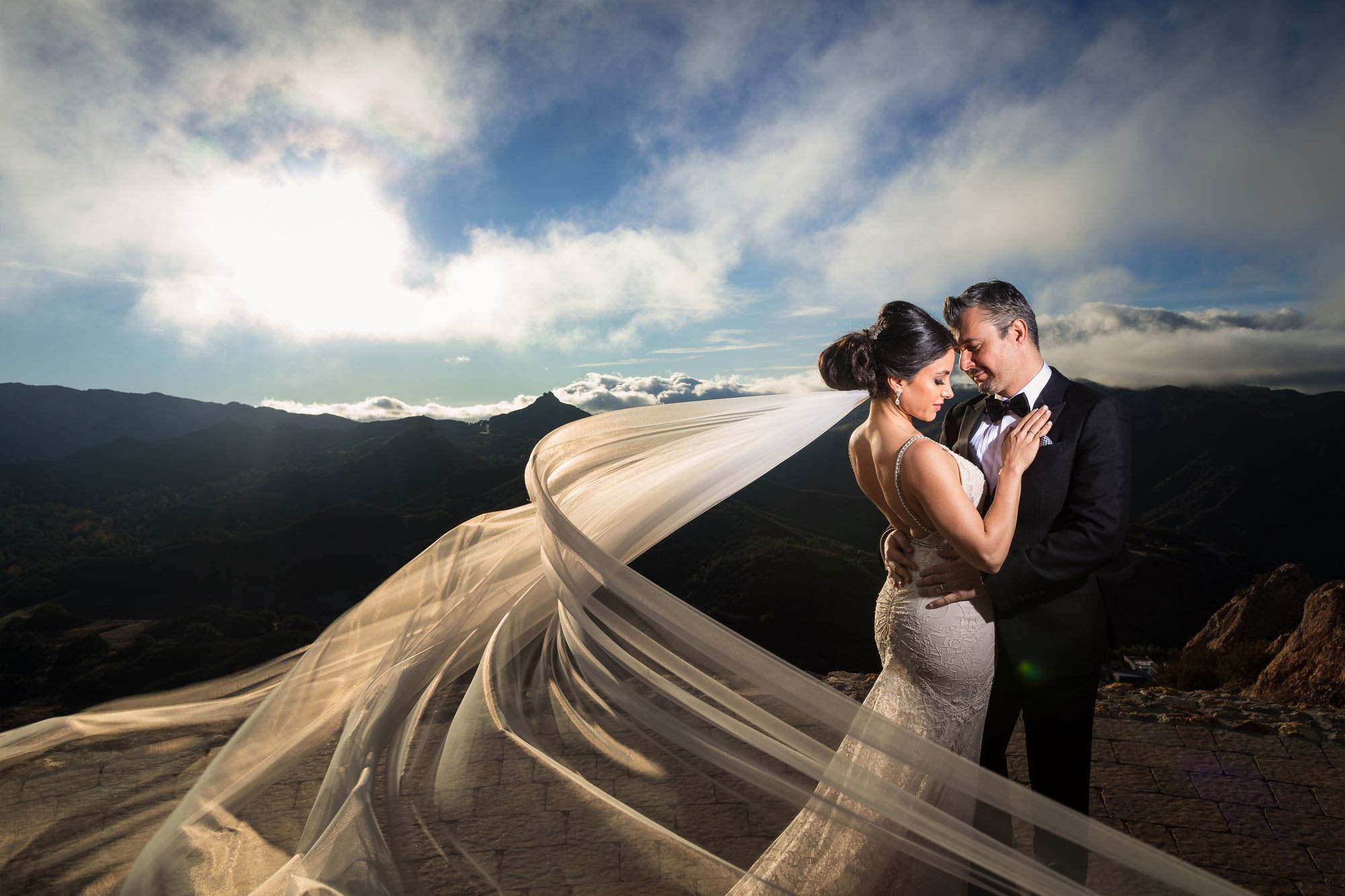 Couple stands in closed pose with veil toss