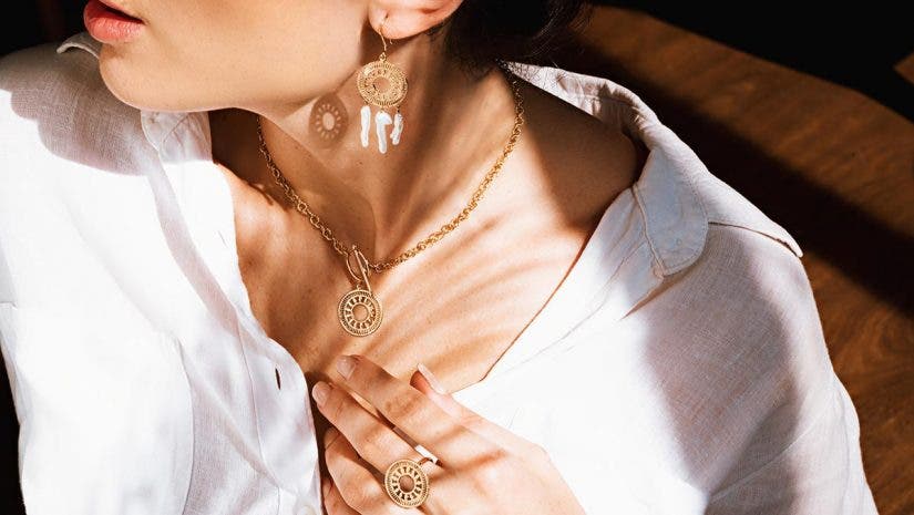 woman modeling gold earrings, necklace, and ring for jewelry photography shoot