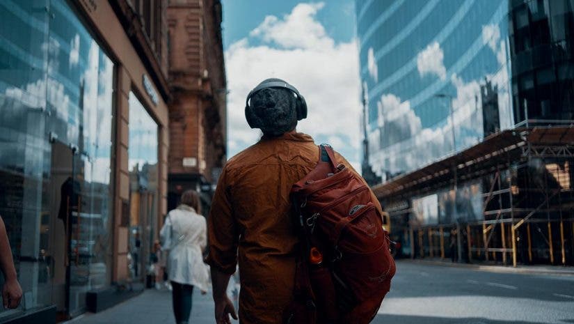 man walking through city with over ear headphones