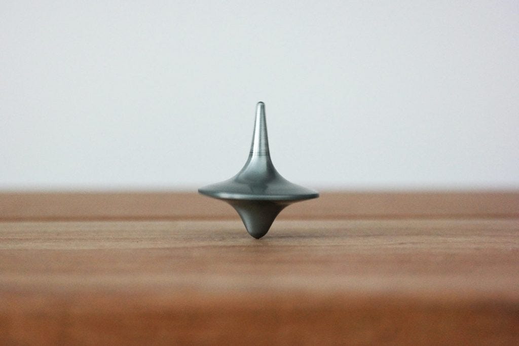 spinning top rotating on the symmetrical balance of the table