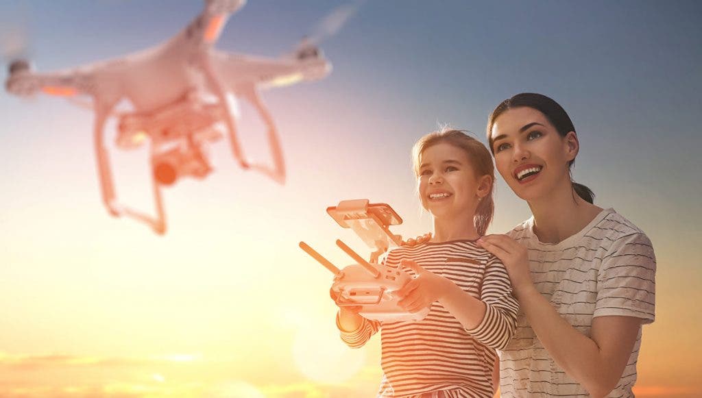 young girl flying a drone with woman