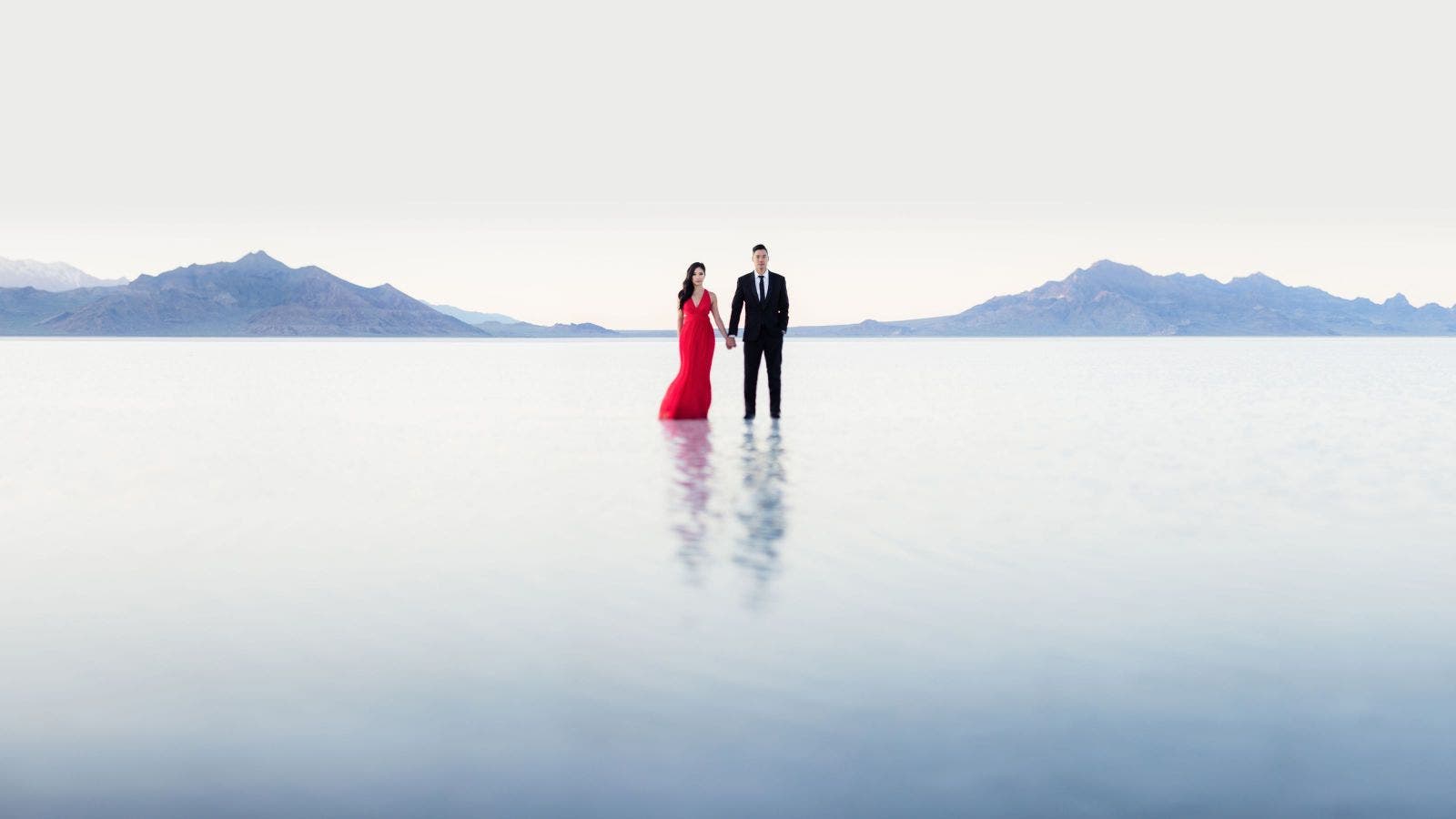 Couple stands over reflection on salt flat
