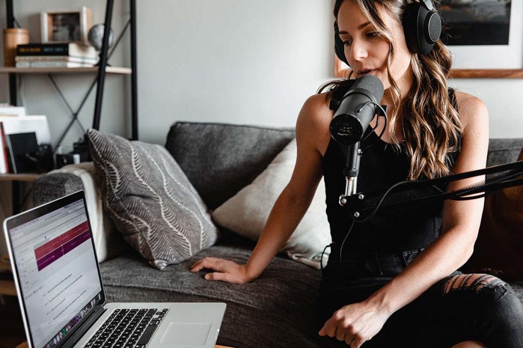 woman recording podcast with microphone and laptop