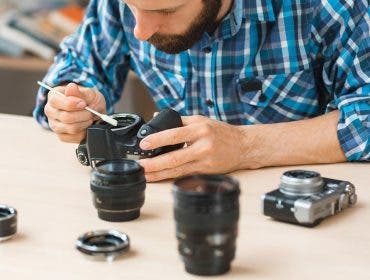 man cleaning camera sensor and lenses with brush and