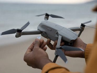 person holding drone on beach with memory card