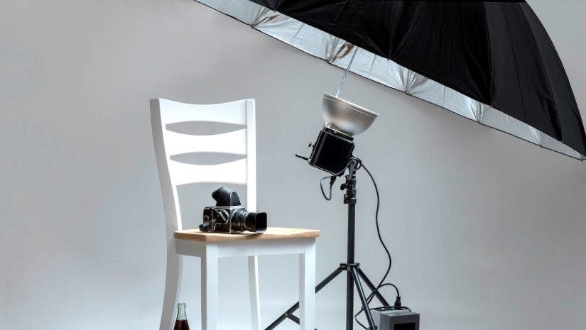 chair and camera posed in photo studio with umbrella