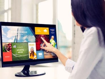 business, people, technology and mass media concept - close up of woman pointing finger to news application on computer monitor in office