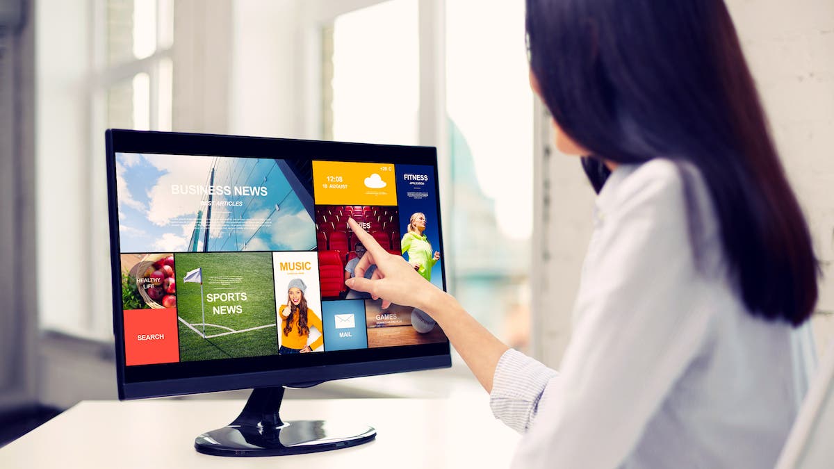 business, people, technology and mass media concept - close up of woman pointing finger to news application on computer monitor in office