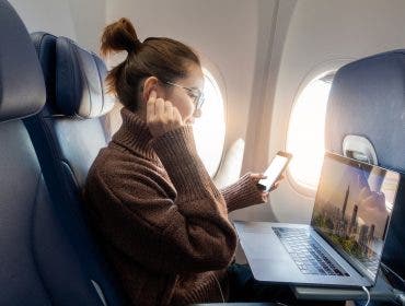 Beautiful Asian woman is working with laptop in airplane