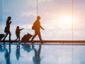 Family at airport travelling with young child and luggage walking to departure gate, girl pointing at airplanes through window, silhouette of people, abstract international air travel concept