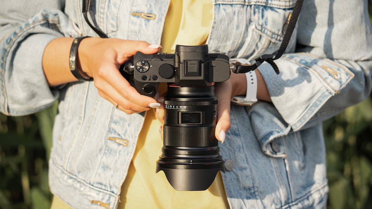 Digital mirrorless camera with a lens in the girl's hands, close-up photo. High quality photo