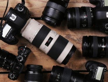 Modern cameras on wooden table, top view