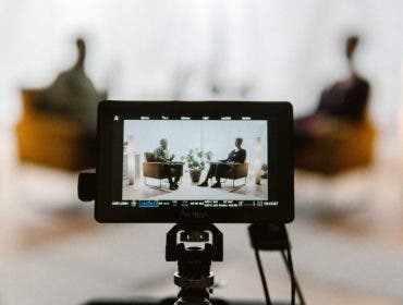 A monitor on top of a camera capturing an interview