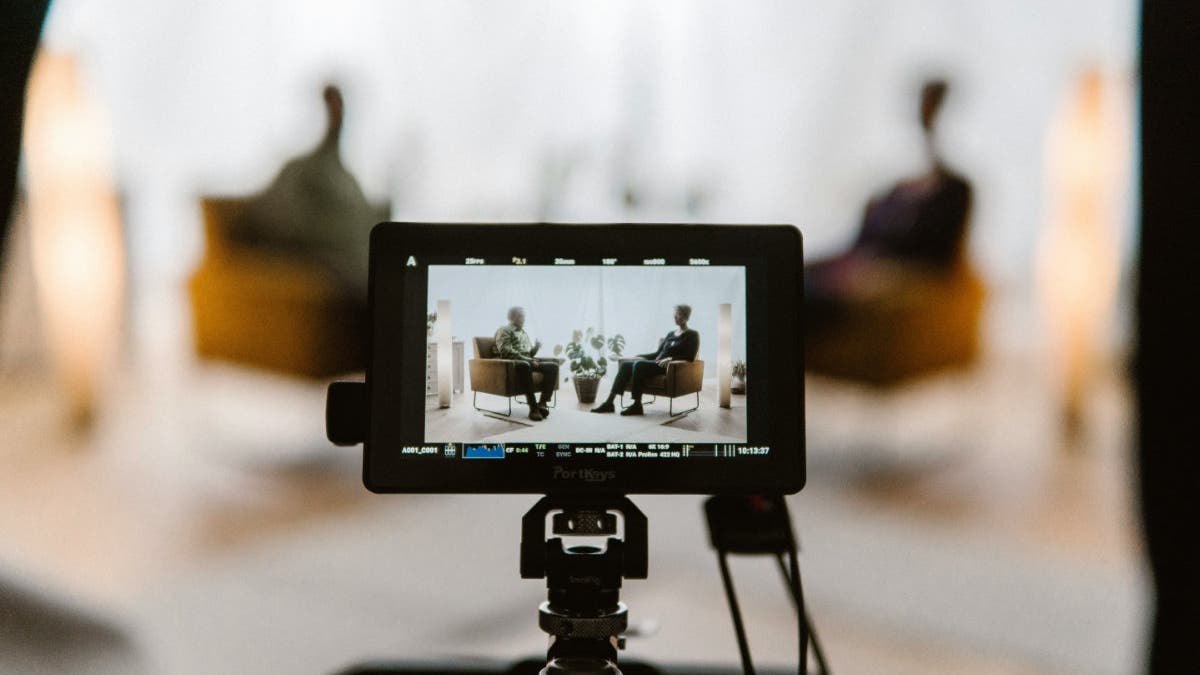 A monitor on top of a camera capturing an interview