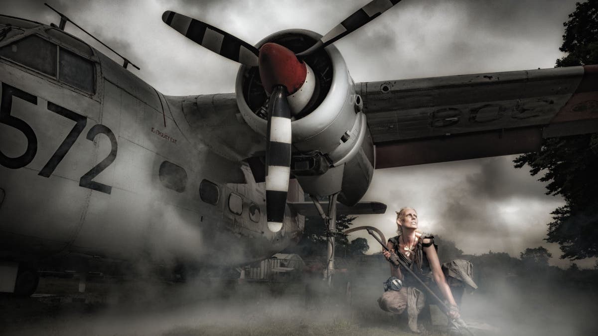 A female model crouched near the propeller of an airplane