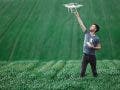 Man-holding-drone-before-flight-in-field-adobe-stock
