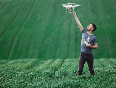 Man-holding-drone-before-flight-in-field-adobe-stock