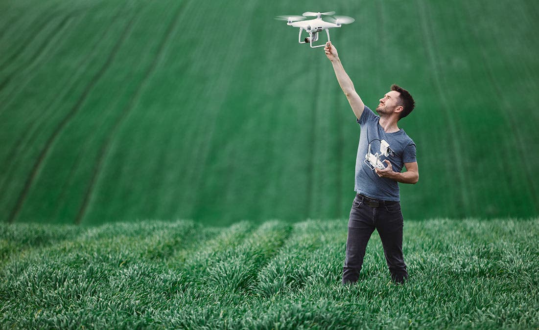 Man-holding-drone-before-flight-in-field-adobe-stock