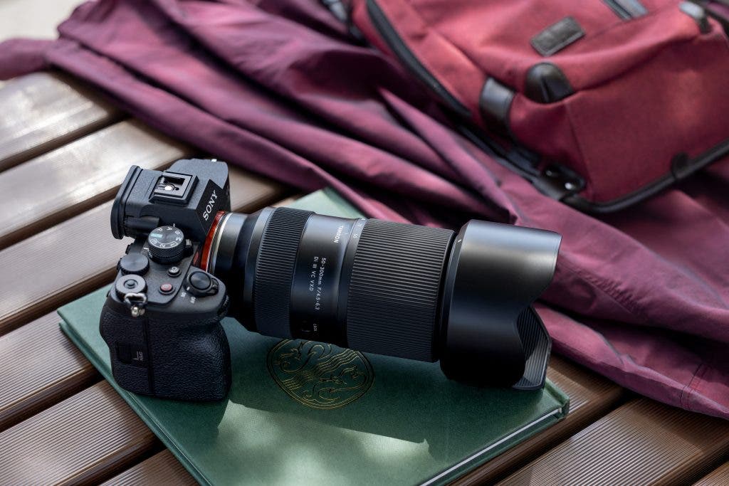 TAMRON 50-300mm F/4.5-6.3 Lens beside a travel bag and book