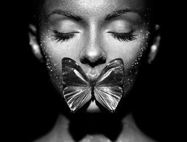 A butterfly lit model with a butterfly between her lips