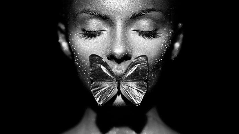 A butterfly lit model with a butterfly between her lips
