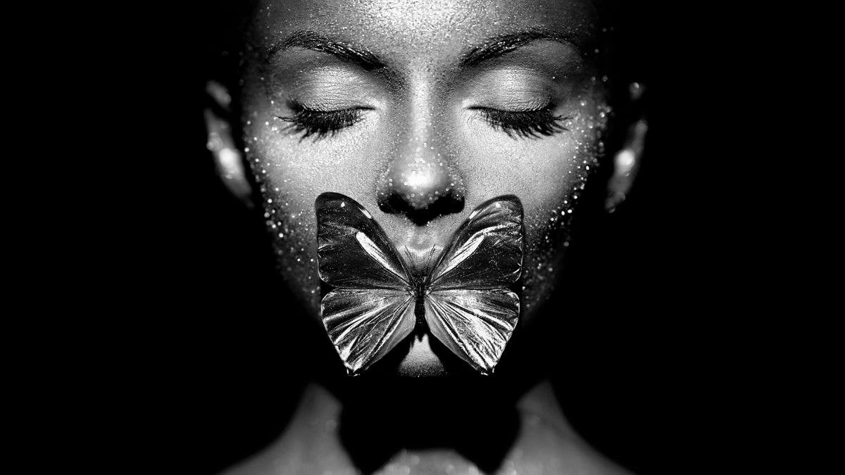 A butterfly lit model with a butterfly between her lips