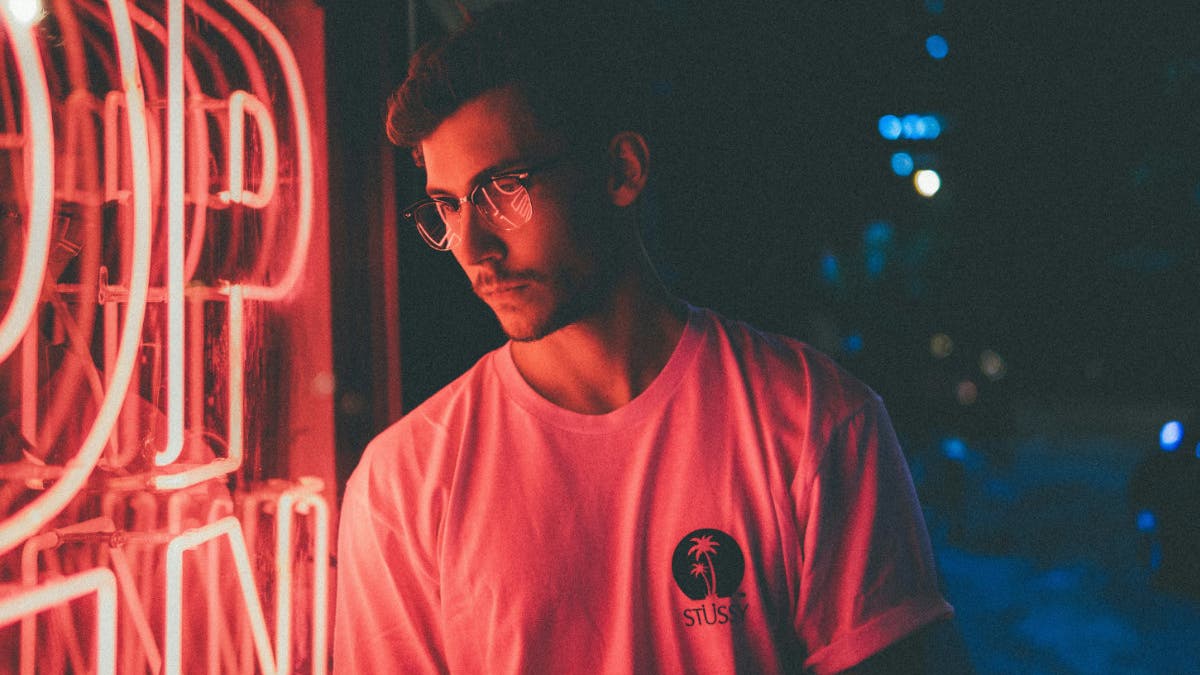 Man is light by the ambient lighting of a neon sigh
