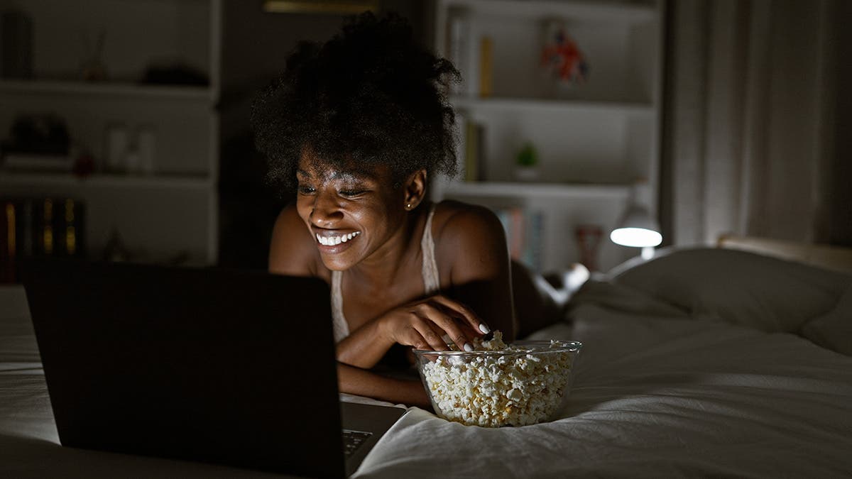woman lit by laptop screen with lamp behind her for practical use of lights via adobe stock.