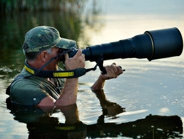 Wildlife photographer holding one of the best lenses for wildlife photography