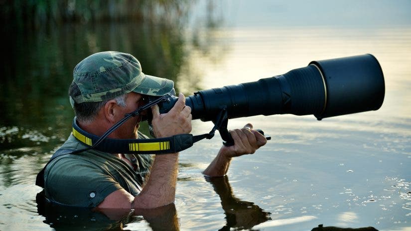 Wildlife photographer holding one of the best lenses for wildlife photography