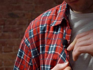 Close-up of man clipping Lavalier microphone to his shirt. Cropped shot of male preparing for interview in tv show attaching lavalier microphone to clothes in studio