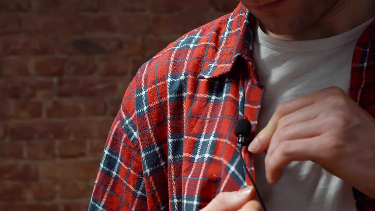 Close-up of man clipping Lavalier microphone to his shirt. Cropped shot of male preparing for interview in tv show attaching lavalier microphone to clothes in studio