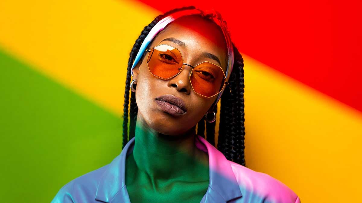 Beautiful afro-american woman with afro pigtails hairstyle and stylish clothes - Portrait of the young black girl in the studio - Color Gels