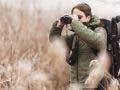 Nature photographer who is looking at the beauty in birds and other animals through binoculars. Explorer looks through binoculars for biodiversity ecosystem. Nature walk scene while using binoculars