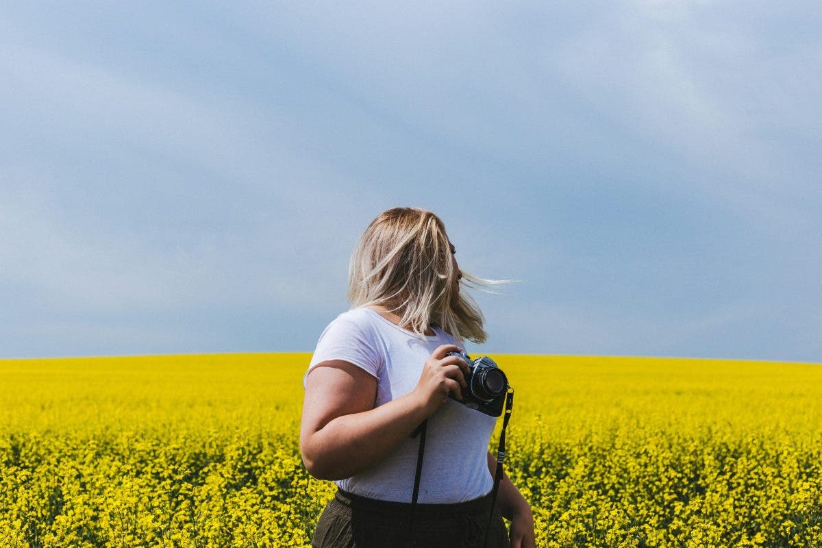 Female photographer looks back on field while holding camera