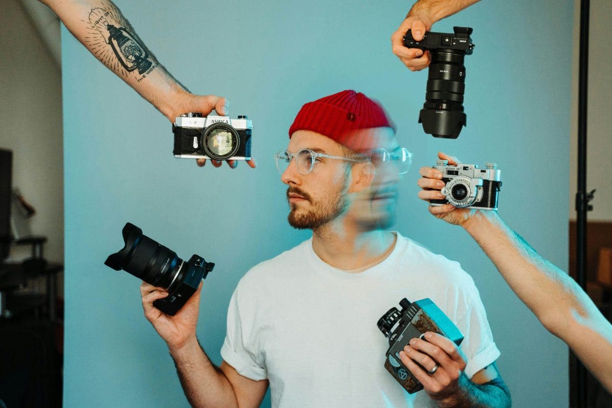 man holding many cameras